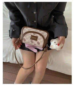 Close-up of retro cream and brown shoulder bag featuring Bread Cat print and bear charm