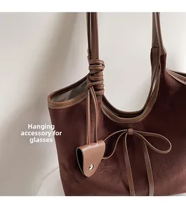 Detail view of large brown faux suede tote bag with bow and leather glasses holder hook