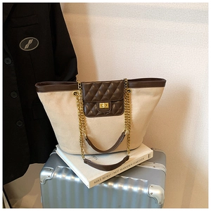 Detail of canvas tote bag with brown quilted leather flap and golden twist lock closure