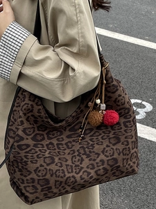 Vintage leopard print tote bag with colorful plush charms and fringe on model