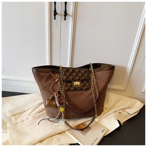 Detail of a brown suede tote bag with quilted front pocket and gold twist lock clasp