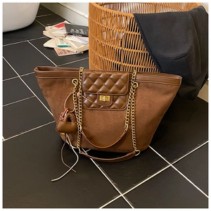 Detail of dark brown suede tote bag with diamond quilting and gold twist-lock closure