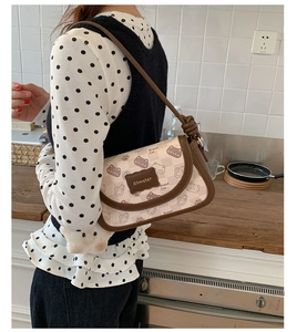 Detail of vintage cream shoulder bag with cat print and unique knotted brown strap