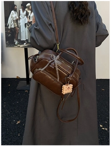 Détail du sac vintage marron avec nœud et breloque biscuit porté par le modèle