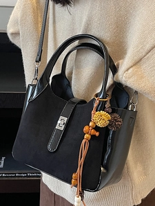Elegant black bucket bag with mixed textures, silver clasp, and bohemian style charms