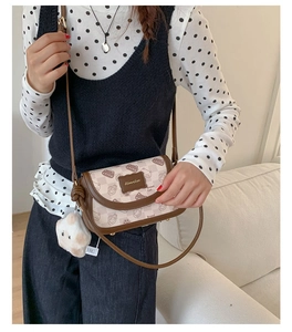 Detail of vintage cat pattern crossbody bag with leather trim and plush pendant