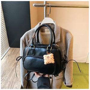 Détail du sac à main noir en cuir PU avec charm biscuit en peluche et ruban à carreaux décoratif