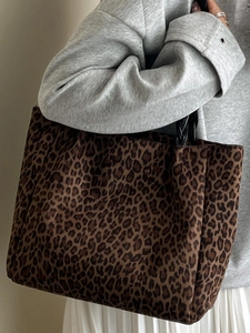 Chic leopard print oversized tote bag with black woven handles shown on shoulder