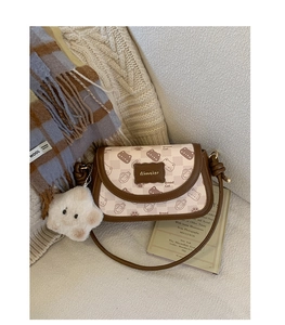 Detail of Bread Cat crossbody bag with plush charm on a cozy knit background