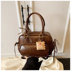 Détails d'un sac Boston marron vintage avec ruban à carreaux et pendentif biscuit peluche
