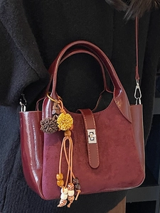 Chic burgundy bucket bag with suede paneling and tassel charm for 2025 winter fashion