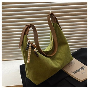 Close-up of green suede hobo bag with adjustable brown strap and vintage beaded charm