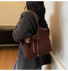 Detail of vintage matte brown tote bag with leather bow and metal beads on model