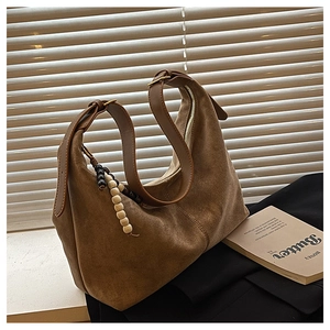Close-up of vintage brown suede hobo bag with leather strap and beaded tassel detail