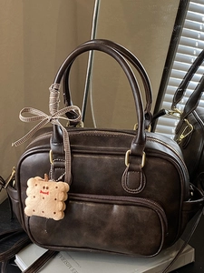 Sac Boston vintage marron avec détails dorés, breloque en peluche et doubles poignées