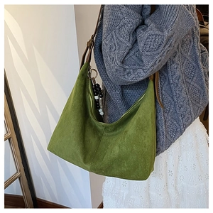 Detail of green suede shoulder bag featuring beaded charm and vintage leather strap