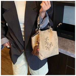Detailweergave van de suède handtas met strikpatronen, franje kwastje en zijden sjaal