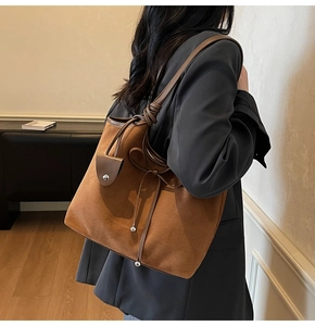 Detail of caramel suede tote bag with leather strap and decorative bow on shoulder