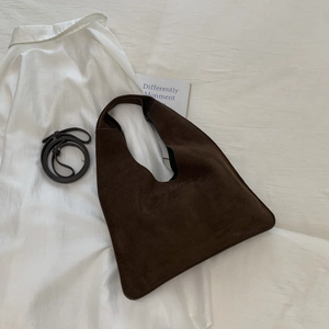 Macro detail of dark brown matte suede tote bag texture with minimalist shoulder strap