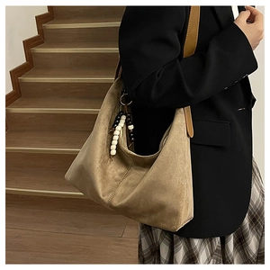 Close-up of vintage brown suede tote bag with stylish black and white beaded tassels