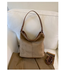 Detailed macro view of brown faux suede tote bag featuring vertical stitching and dual straps