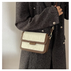 Détail d'un sac bandoulière rétro en fausse fourrure blanche et cuir marron contrasté