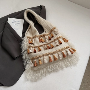 Detail of bohemian knit tote bag with layered fringes and ethnic style tassel accents