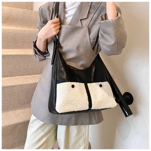 Close-up of a minimalist black and white faux fur patchwork tote bag worn over the shoulder