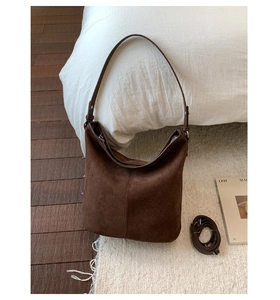 Detail of dark brown suede hobo bag featuring wide strap and adjustable shoulder strap