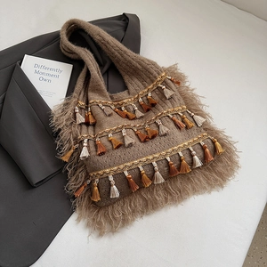 Detail of bohemian knit tote bag with colorful tassels and soft faux fur trim texture