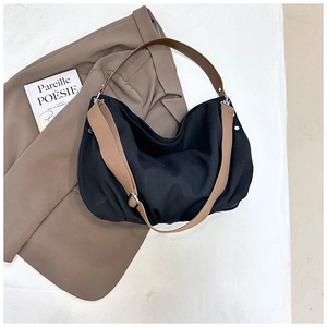 Detail of black canvas tote bag with brown leather handles on a vintage brown blazer