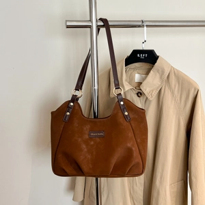 Dettaglio della borsa tote in pelle scamosciata marrone con etichetta e rivetti dorati