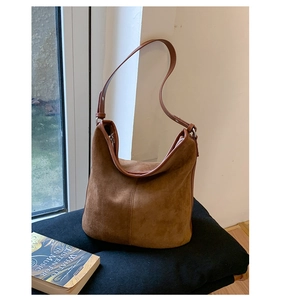 Detailed view of a retro brown suede hobo bag placed next to a book in natural light