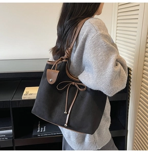 Detail view of large vintage black canvas tote bag with brown leather bow and strap