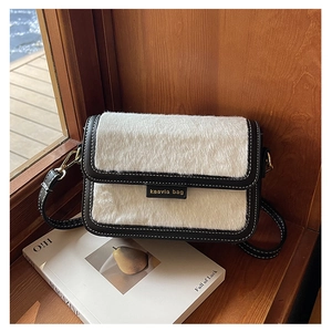Gros plan du sac carré contrasté avec texture en fausse fourrure et logo doré chic