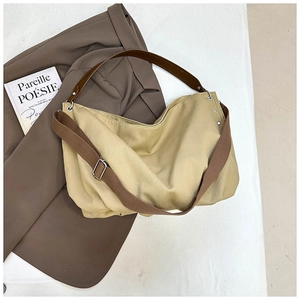 Detail of canvas hobo tote with brown PU leather handle and metal zipper on white background
