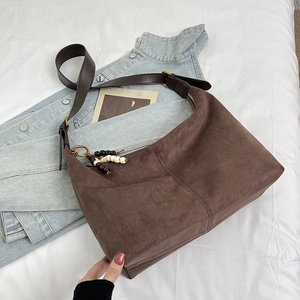 Detail of coffee brown suede tote bag with leather strap and bohemian beaded pendant charm
