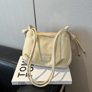 Detail view of cream leather shoulder bag with fine strap and elegant metal hardware