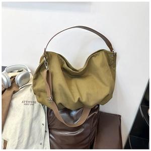 Detail of olive green canvas tote bag with brown leather handles and adjustable strap