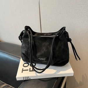 Close-up of black suede underarm bag with double slim straps and side drawstring detail