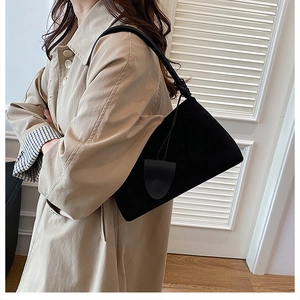 Detail der minimalistischen schwarzen matten Schultertasche mit Blattanhänger am Model
