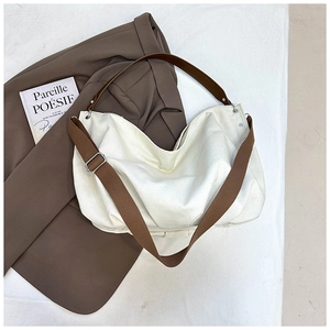 Detail of white canvas tote bag with brown leather straps and adjustable crossbody belt