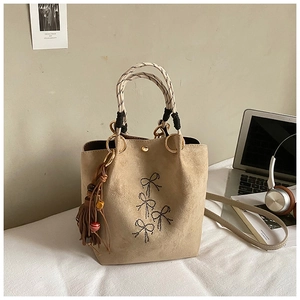 Detail van kaki bucket bag met strikborduurwerk en geweven handvat in een setting