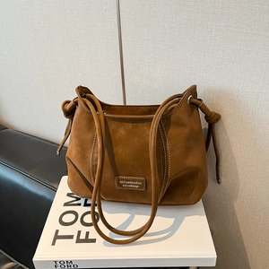 Detail of caramel brown bag with contrast stitching and decorative side knot detail