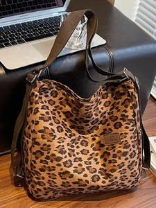 Detail of leopard print tote bag featuring side pockets and adjustable brown webbing strap