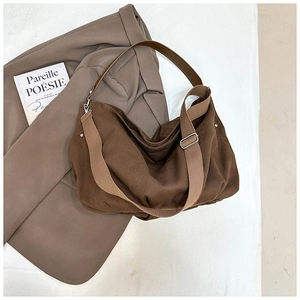 Flat lay of brown canvas tote bag showing wide woven strap and zipper closure