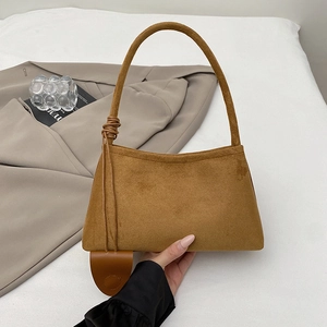 Detail einer braunen matten Leder-Achseltasche mit dekorativen Knoten und Lederanhänger