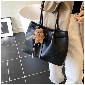 Detail of black suede tote bag with cute brown teddy bear charm and pearl necklace detail