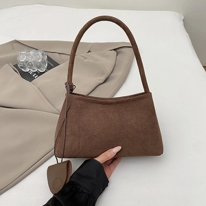 Nahaufnahme braune Wildleder-Unterarmtasche mit minimalistischer Textur und Mini-Charm