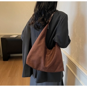 Detail of a large brown suede hobo tote bag featuring wide shoulder straps and soft texture